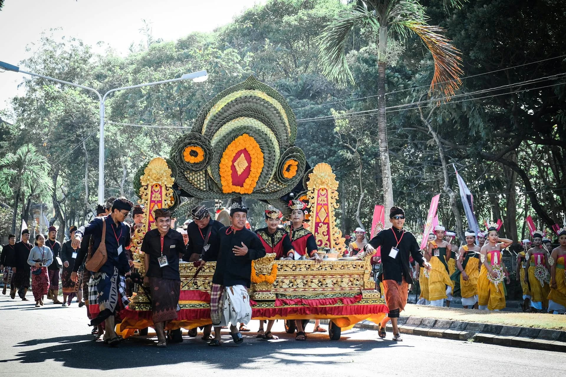 Colorful Balinese parade showcasing traditional costumes and decorations, celebrated outdoors under sunny skies.